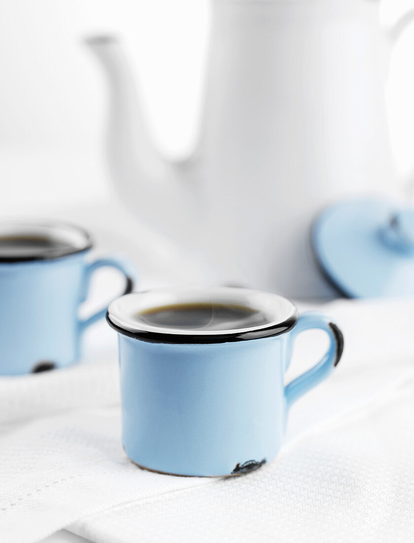 Kaffee in blauen Tassen vor weisser Kaffeekanne
