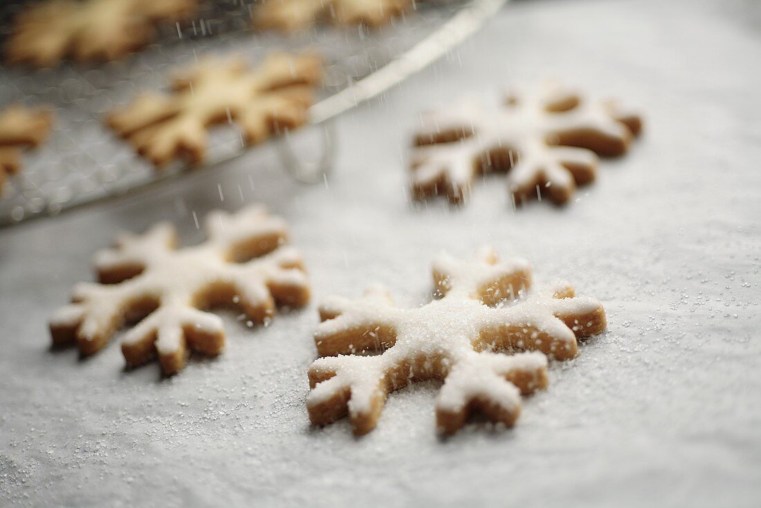 Sprinkling snowflake biscuits with sugar