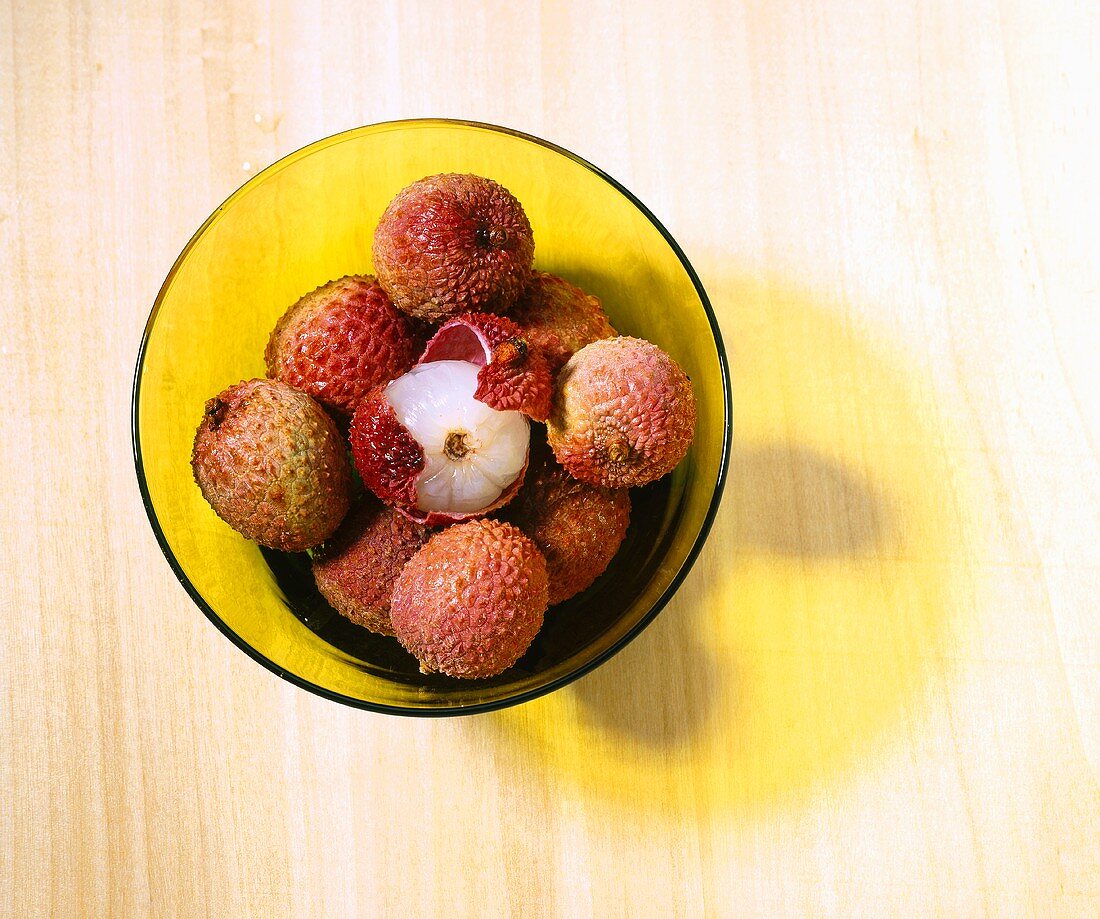 Lychees in gelber Glasschale (Draufsicht)