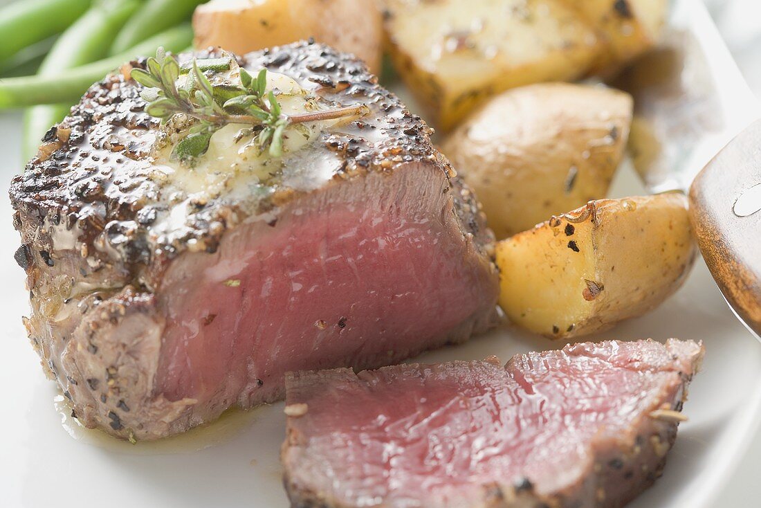 Peppered steak, a piece cut off, with roast potatoes