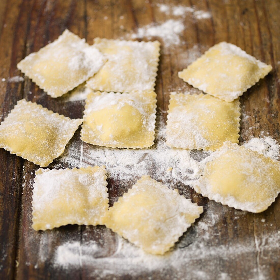 Selbstgemachte Ravioli mit Mehl auf Holzuntergrund