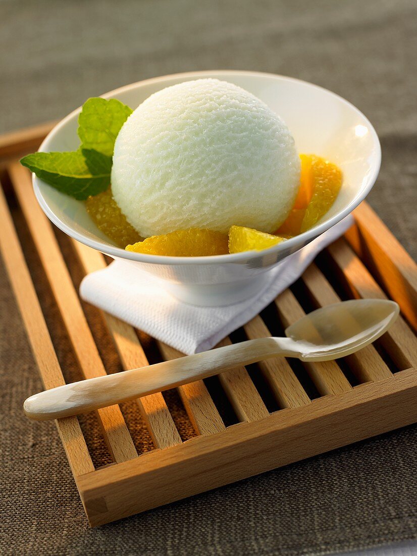 Tea ice cream with orange segments in a white bowl
