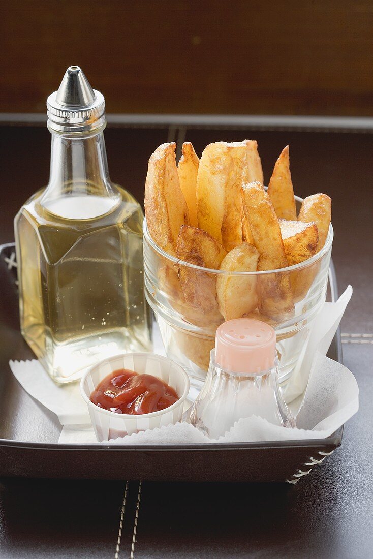 Potato wedges in a glass, salt, ketchup, oil