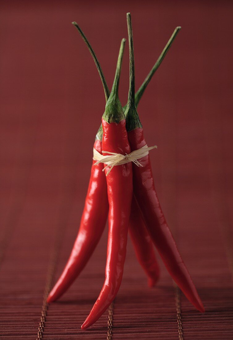 Four chillies, tied together, on red bast mat