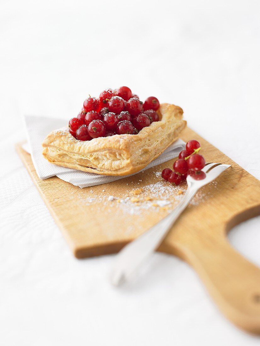 Blätterteiggebäck mit Johannisbeeren auf Schneidebrett