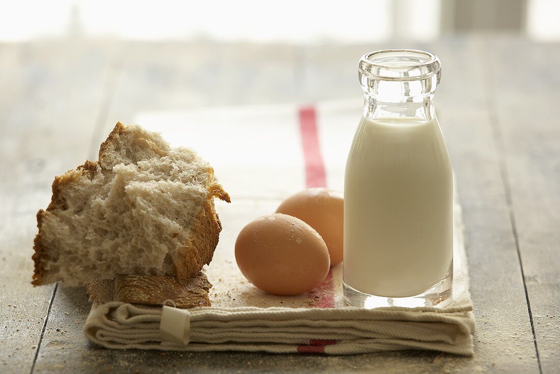 Flasche Milch, Eier und Brot auf Geschirrtuch