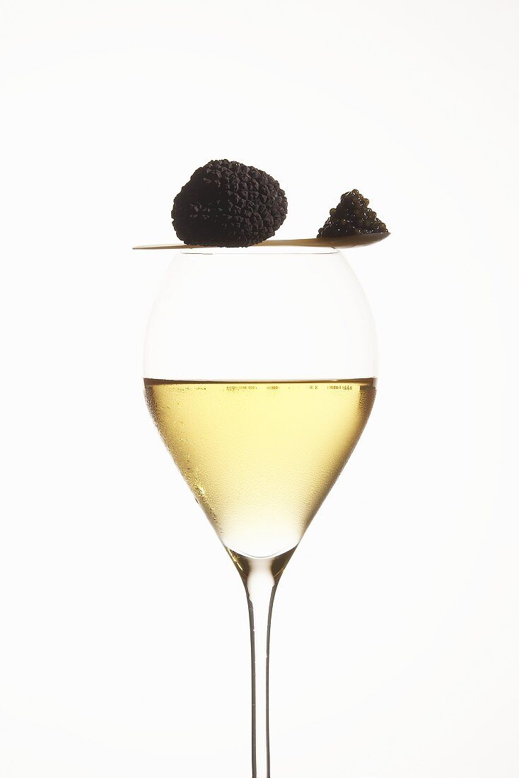 Black truffle and spoonful of caviar on glass of champagne