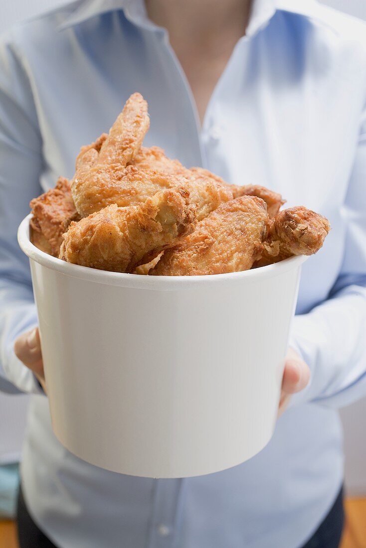Woman holding deep-fried chicken pieces