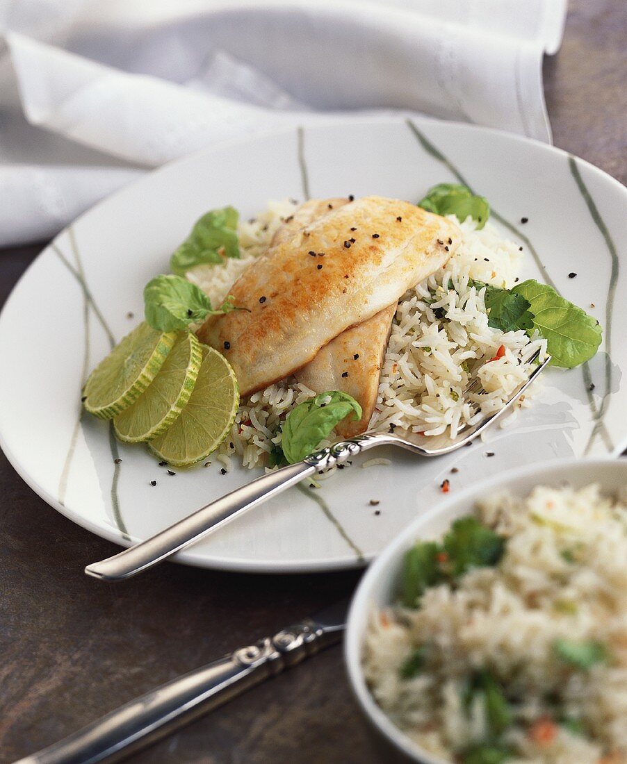 Fish fillet with slices of lime on basmati rice