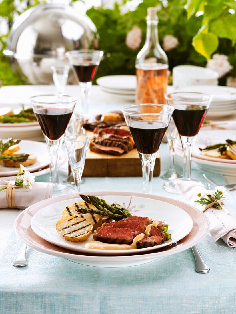 Grilled beef on laid table out of doors