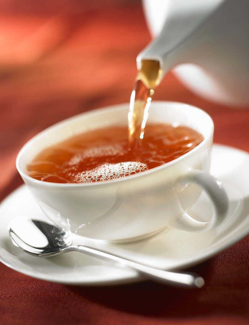 A cup of black tea being poured