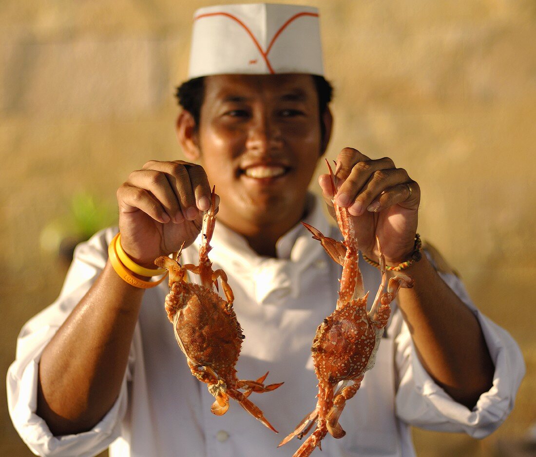 Thailändischer Koch mit zwei Taschenkrebsen