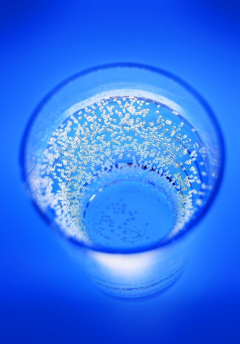 A glass of mineral water against a blue background