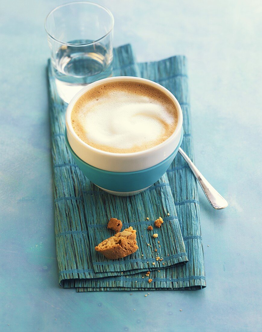 Milchkaffee in einer blau-weiss gestreiften Schale