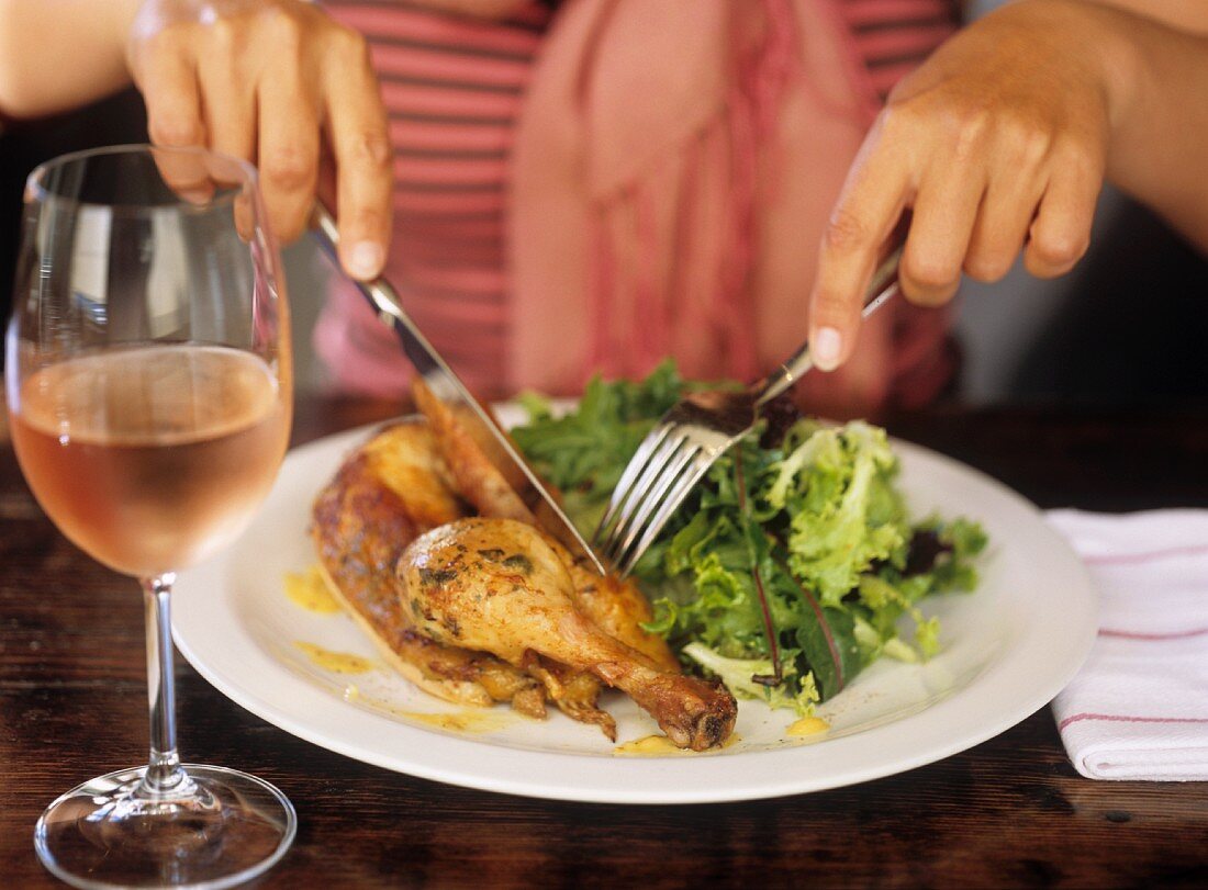 Frau isst Grillhähnchen mit Salat