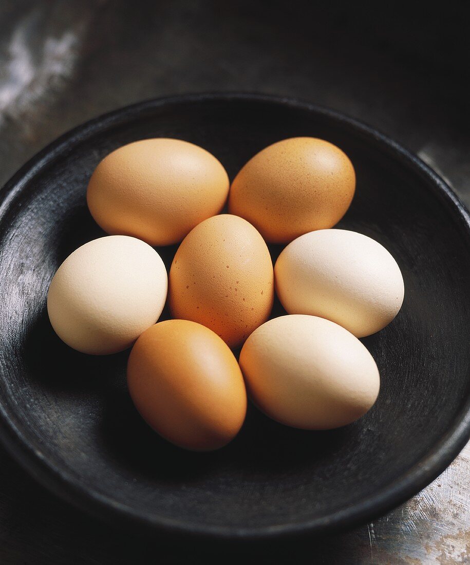 Several brown and white eggs in a dish