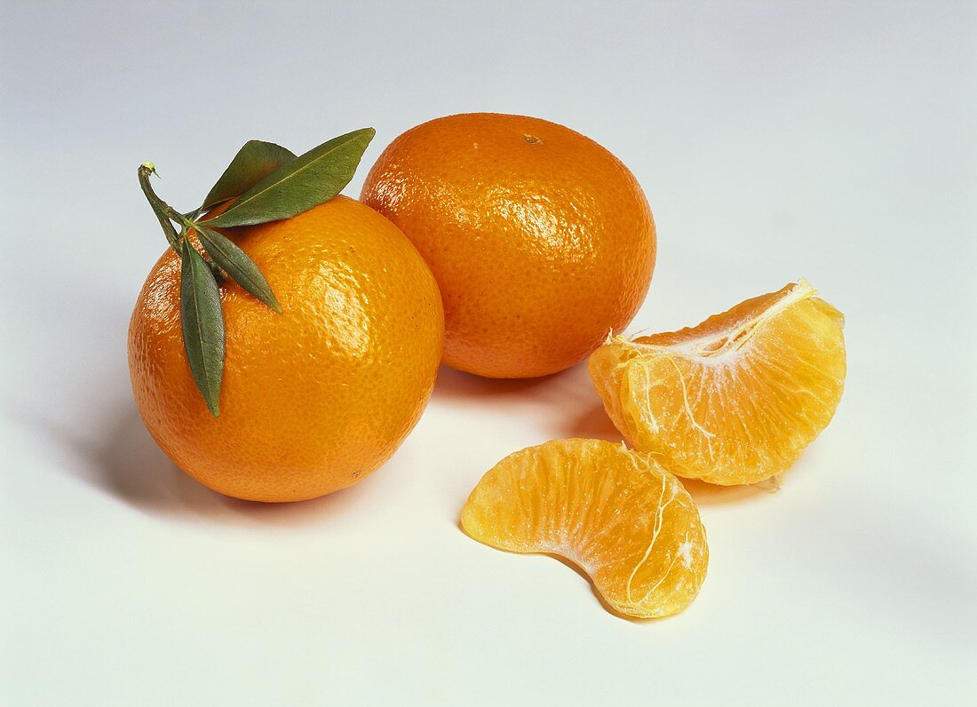 Two whole mandarins and mandarin wedges