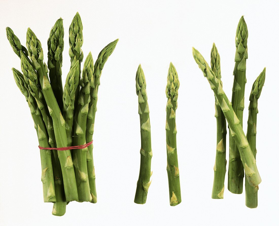 Several spears of green asparagus on white background