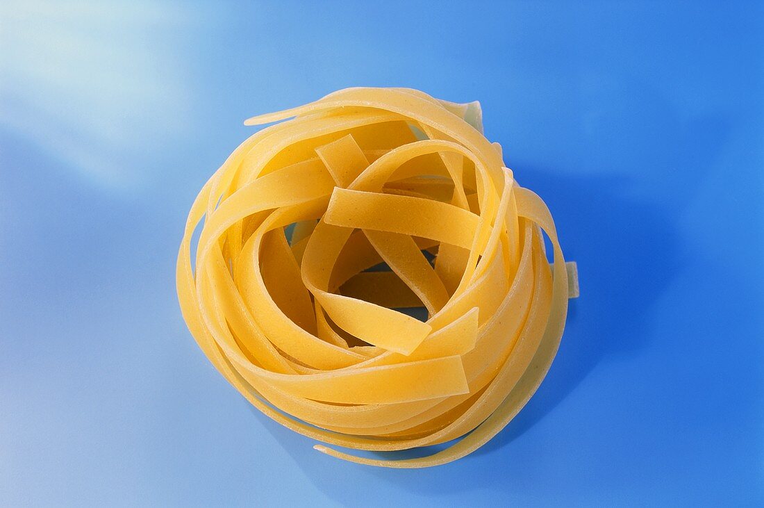 Tagliatelle rolled up on blue background