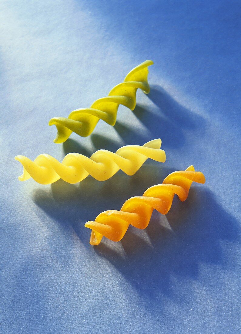 Three coloured fusilli on blue background