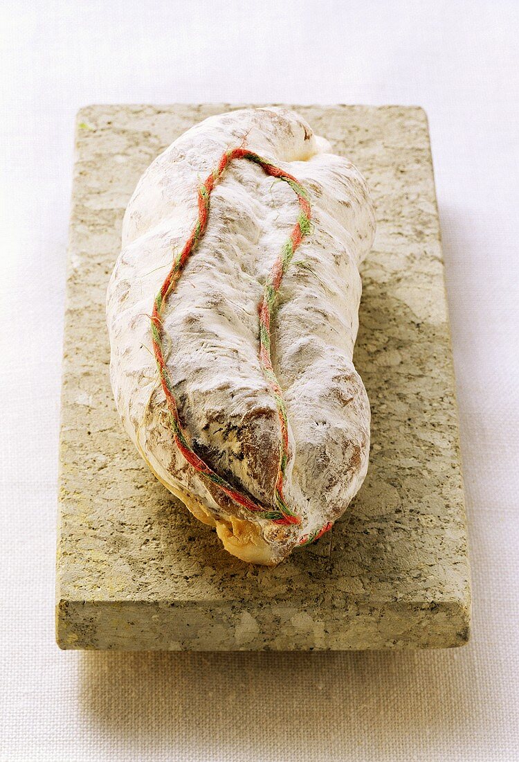 A whole Italian salami on a stone slab