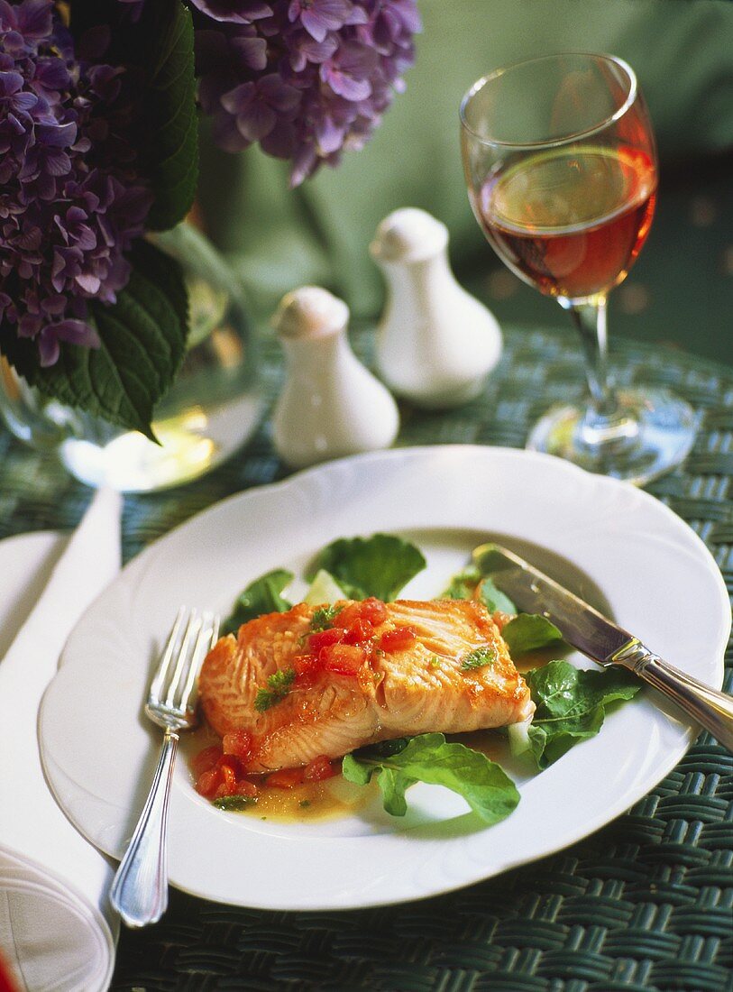 Poached salmon fillet with tomato sauce on leafy vegetables 