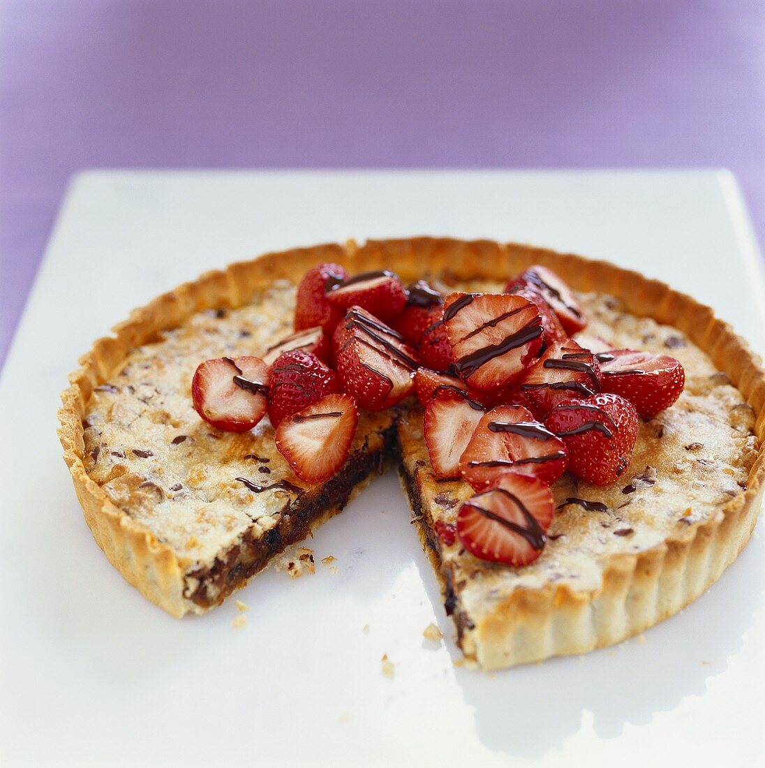 Chocolate and walnut tart with strawberries, a piece cut