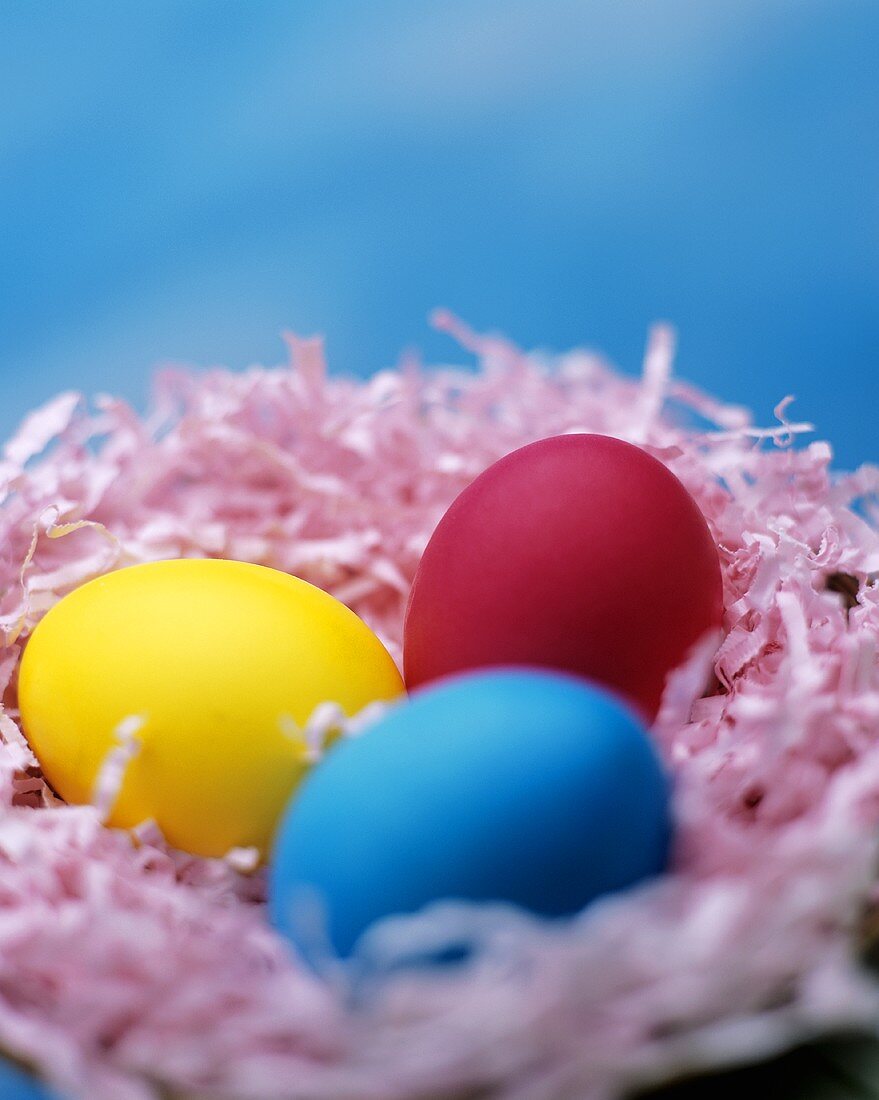 Three coloured Easter eggs in an Easter nest