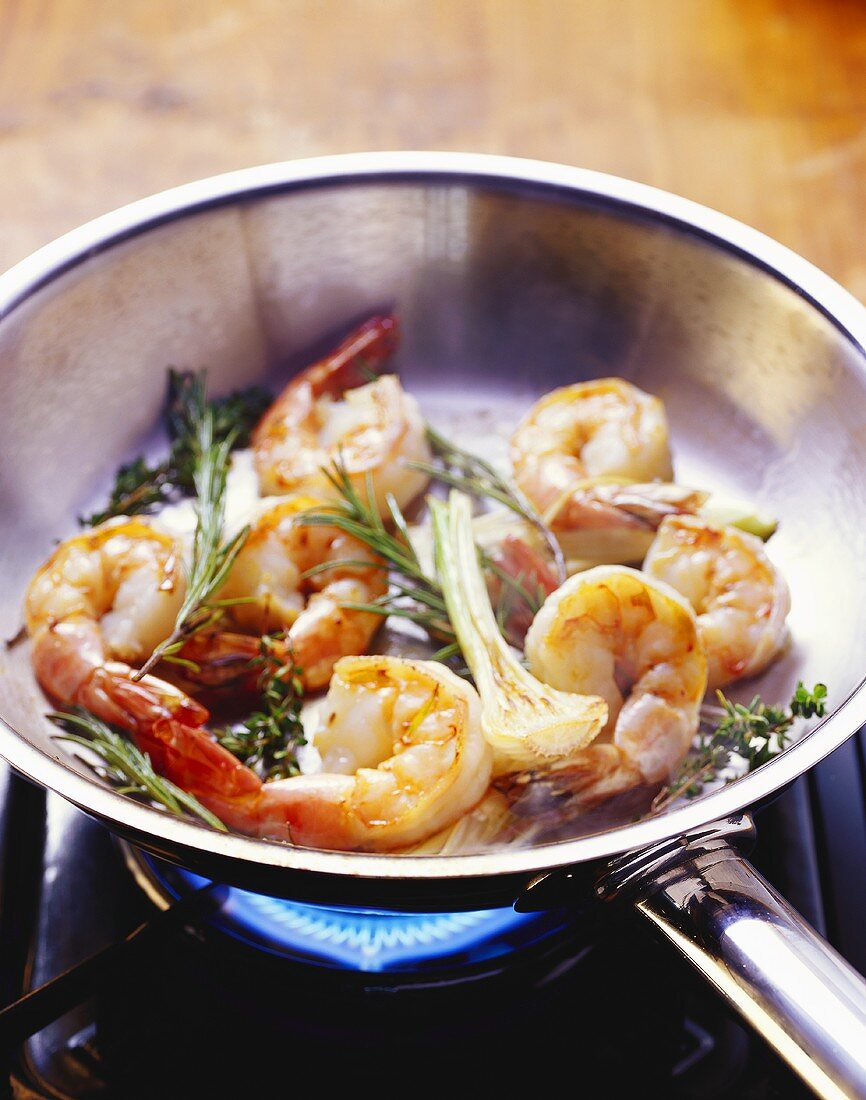 Frying shrimps with herbs in a frying pan