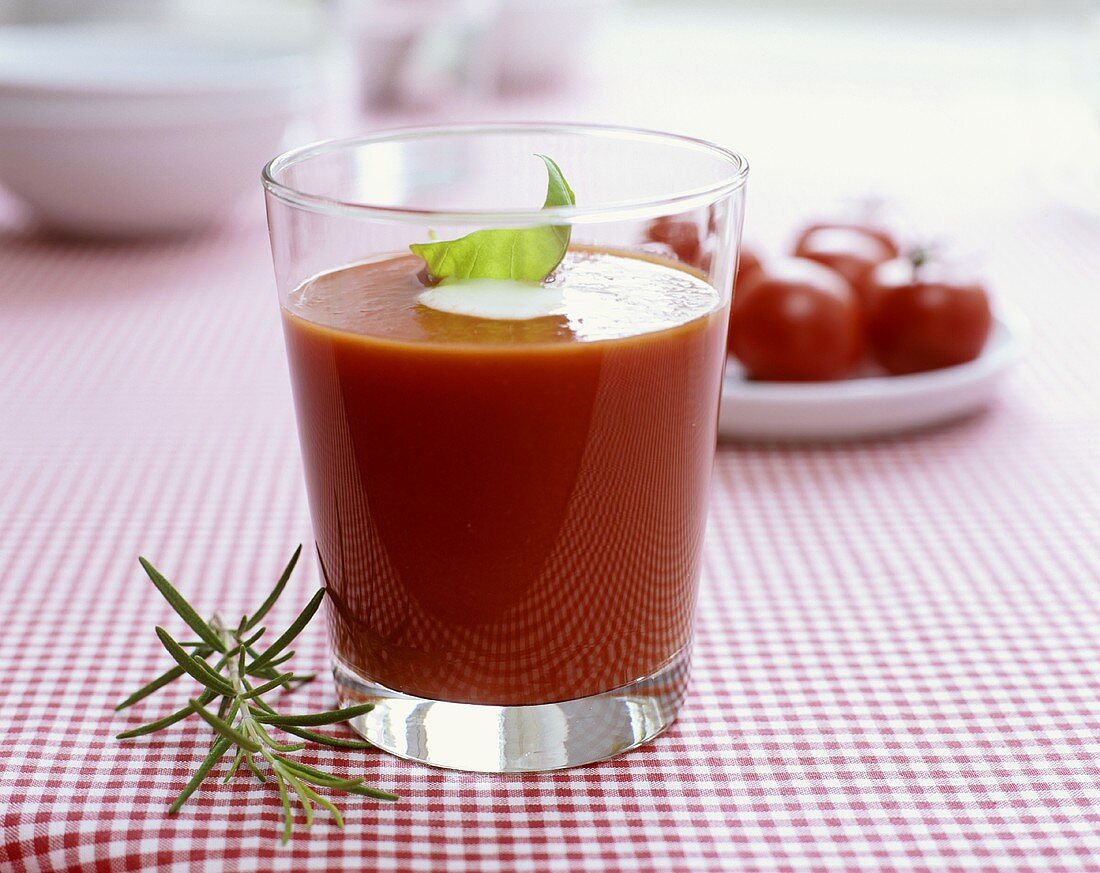 Tomatensuppe in einem Glas auf rotkarierter Tischdecke
