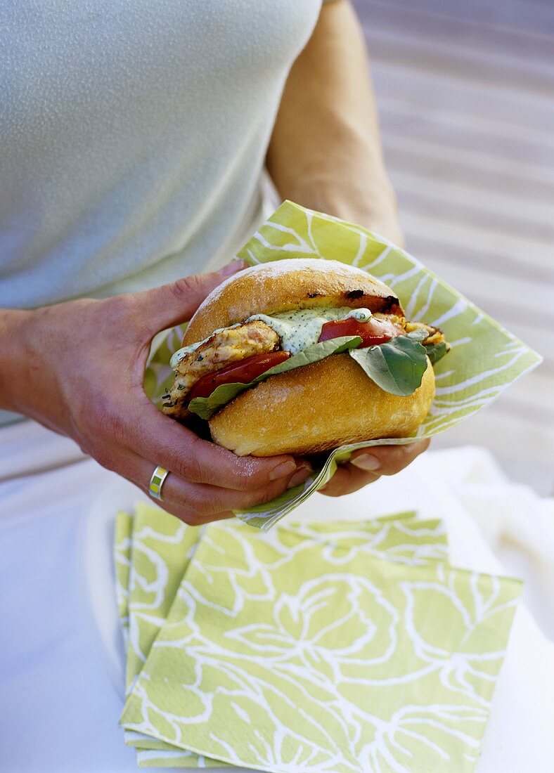 Frau hält Hühnchenburger mit Rucola-Mayonnaise