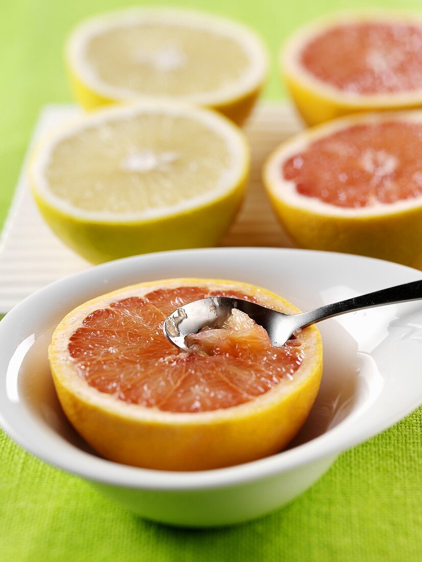 Spoon in a grapefruit half and four grapefruit halves