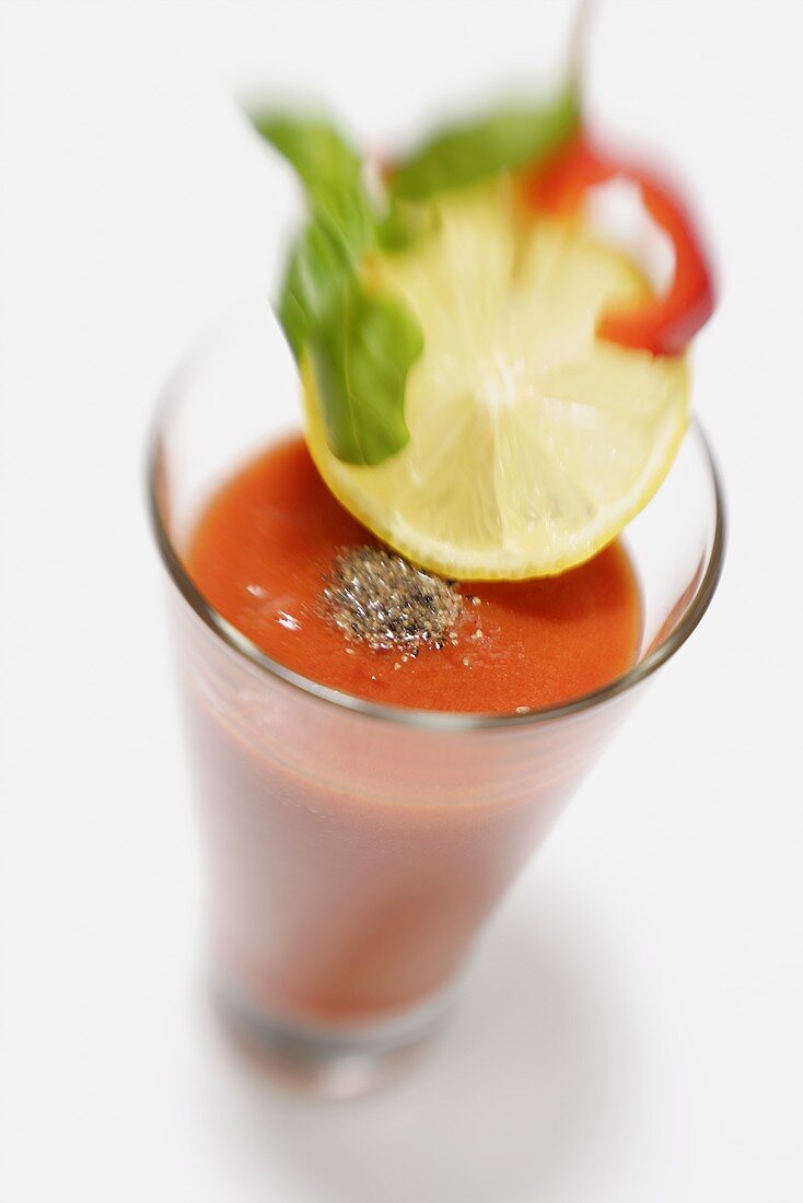 A glass of pepper & tomato juice with slice of lemon & pepper