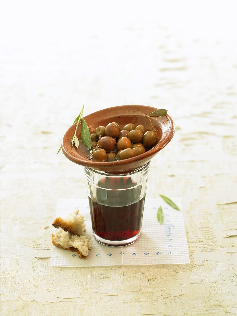 A small bowl of green olives on a glass of wine
