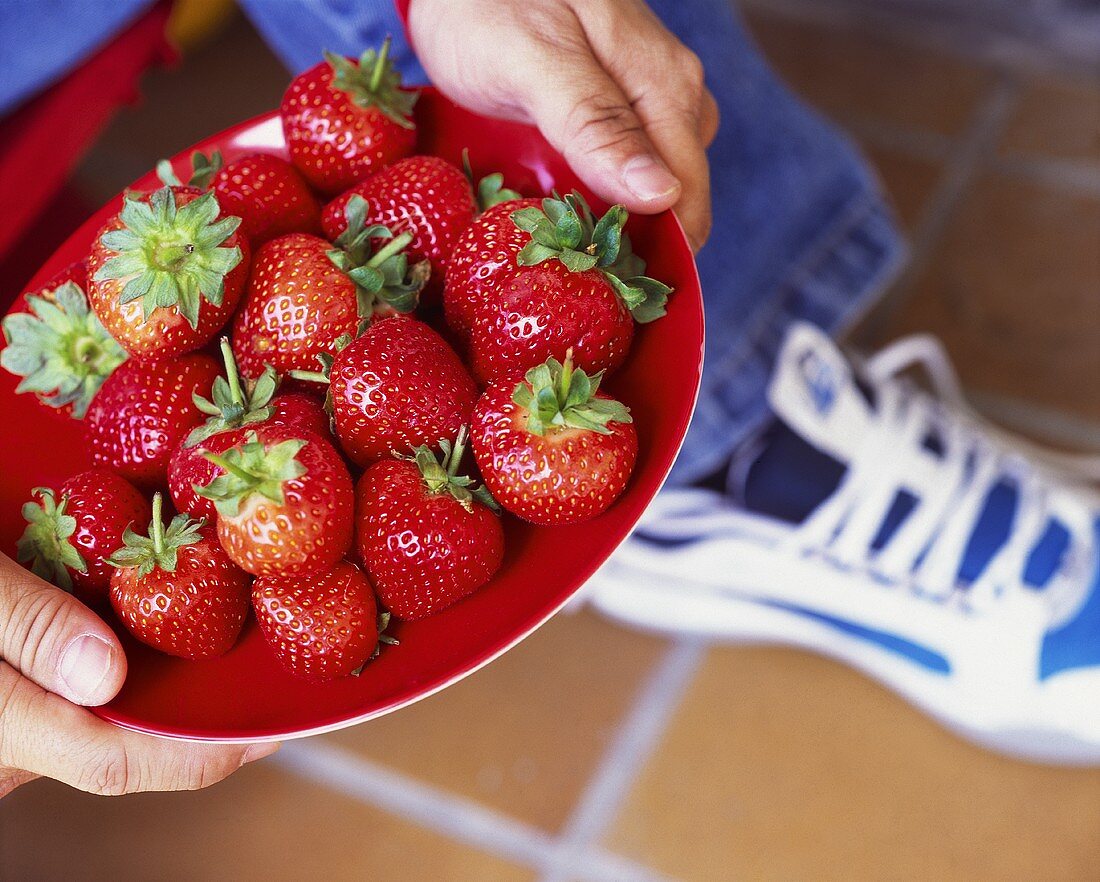 Mann hält Teller mit Erdbeeren