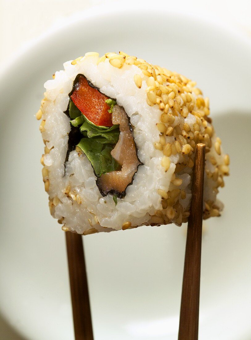 Inside-out roll with fish between chopsticks