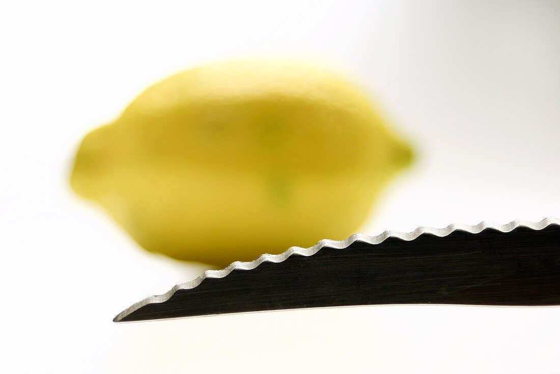 Eine Messerspitze mit einer Zitrone im Hintergrund