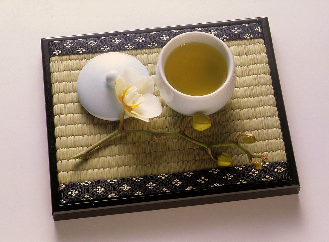 Eine Schale grüner Tee auf Bambusmatte