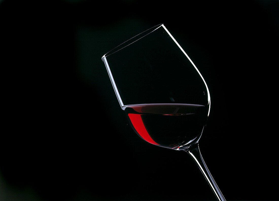Tipped Glass of Red Wine; Black Background