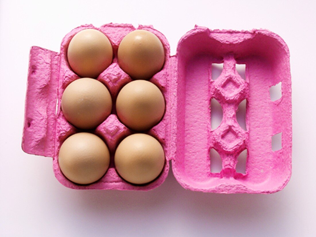 Braune Eier im rosa Eierkarton (Draufsicht)