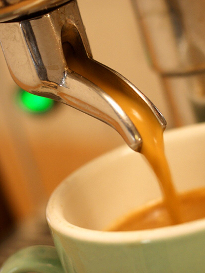 Espresso fliesst aus Espressomaschine in Tasse