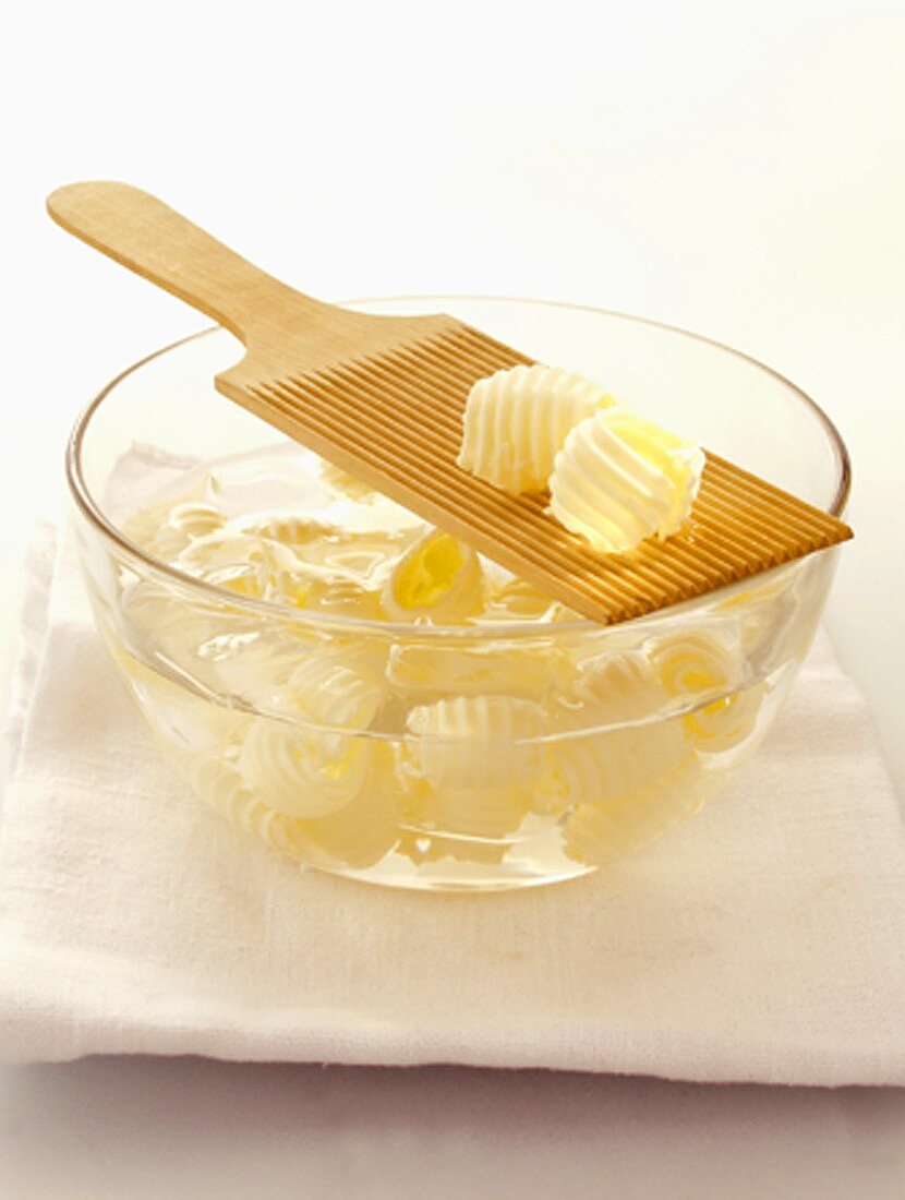Butter Curls in a Bowl of Water and on Wooden Spatula