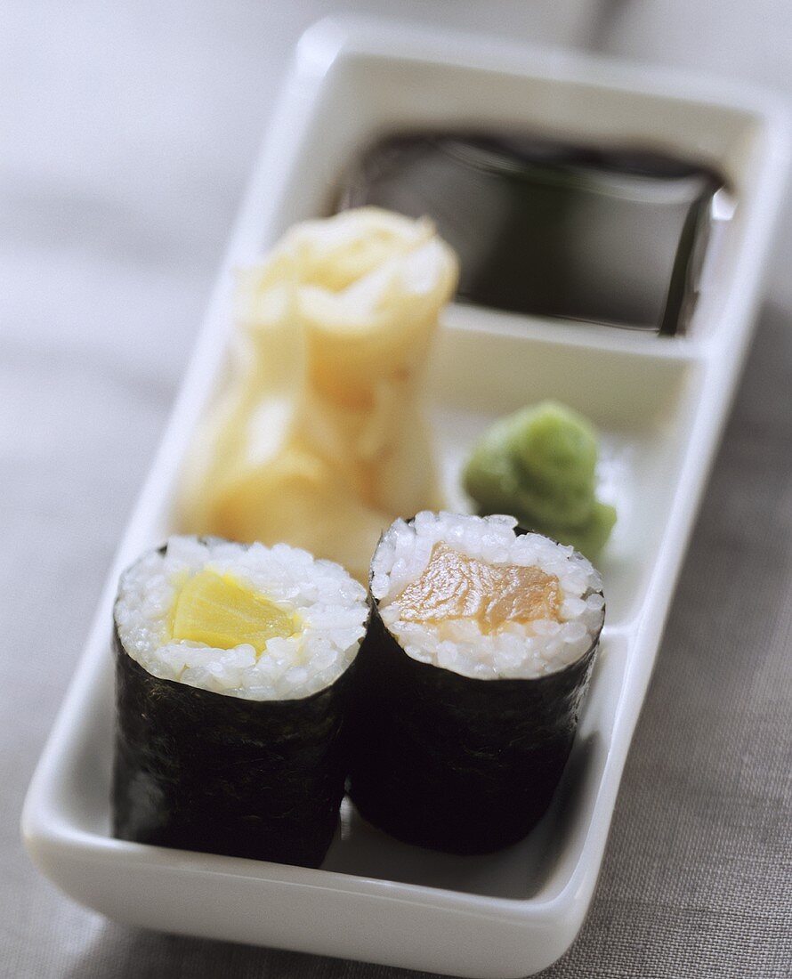 Zwei Maki-Sushi mit Wasabi, eingelegtem Ingwer und Sojasauce