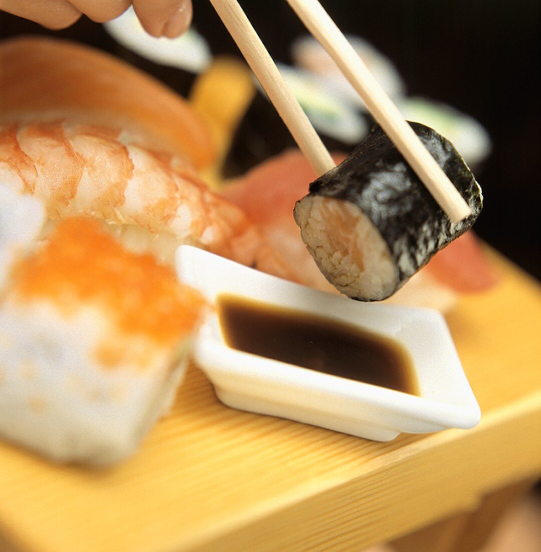 A Hand Dipping Sushi