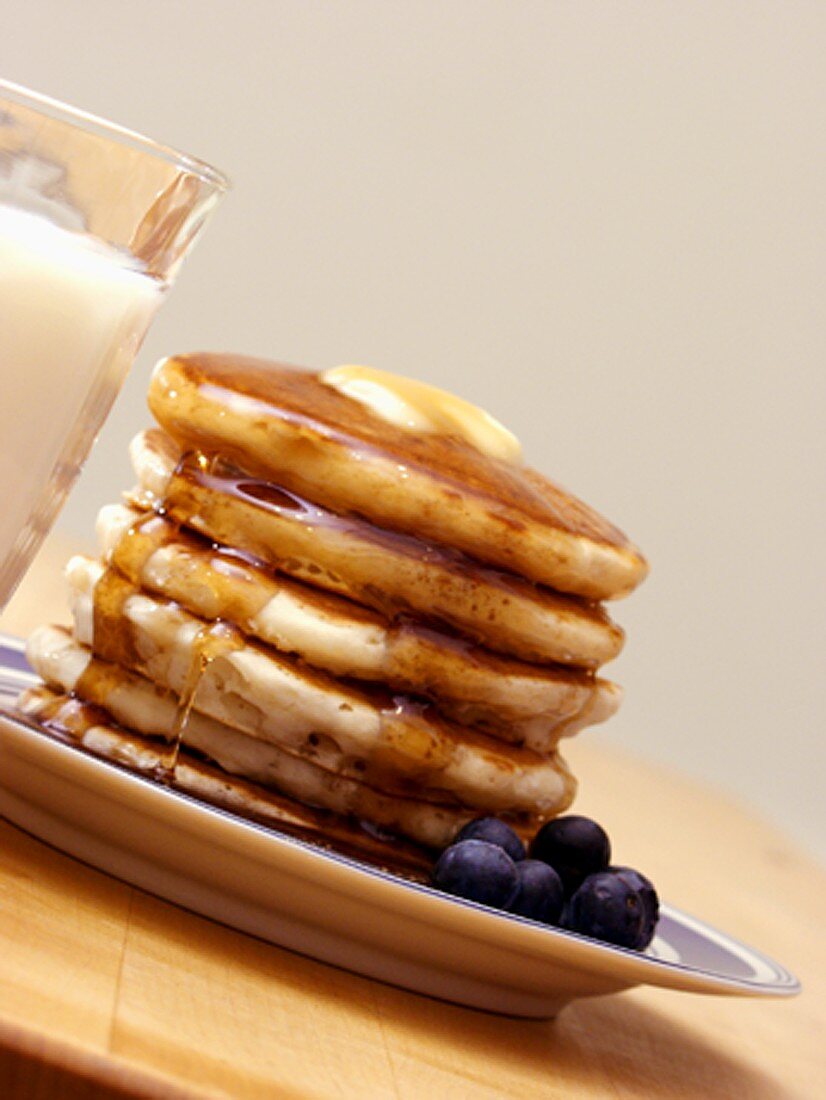 Pancakes mit Ahornsirup, Butter und Heidelbeeren; Milch