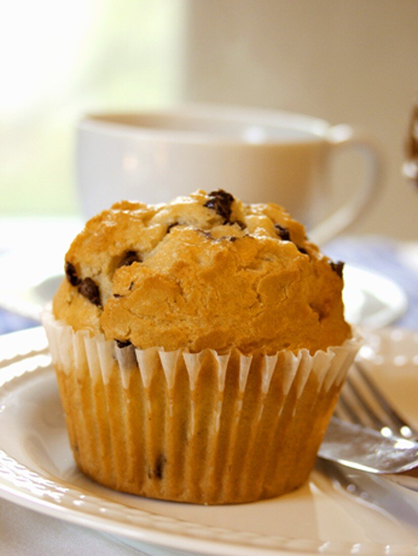 Chocolate Chip Muffin auf Teller vor Kaffeetasse