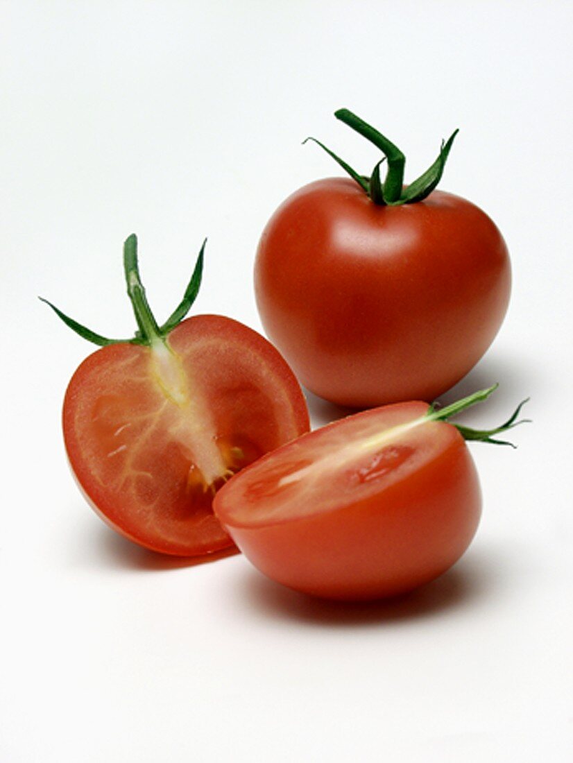 Ganze Tomate und zwei Tomatenhälften