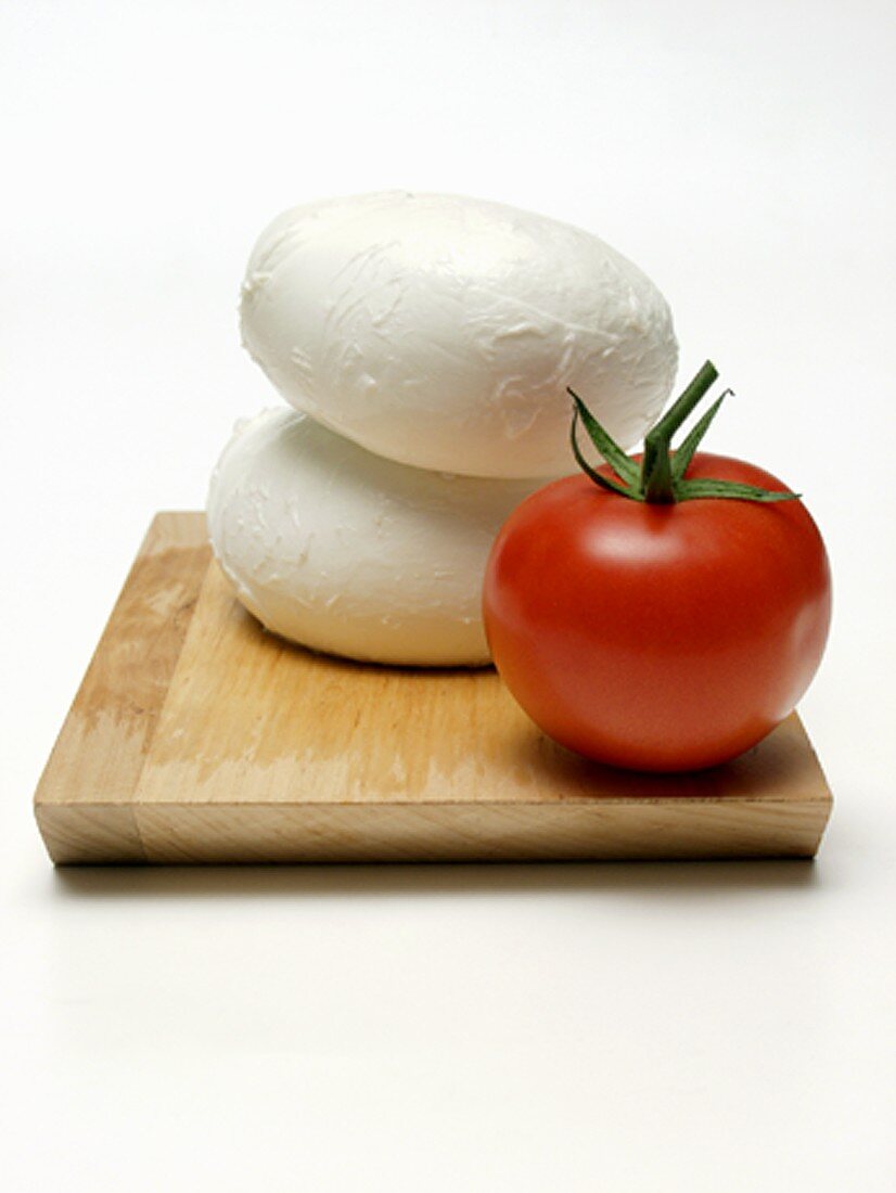 Two Mozzarella Balls with a Tomato on Wooden Board