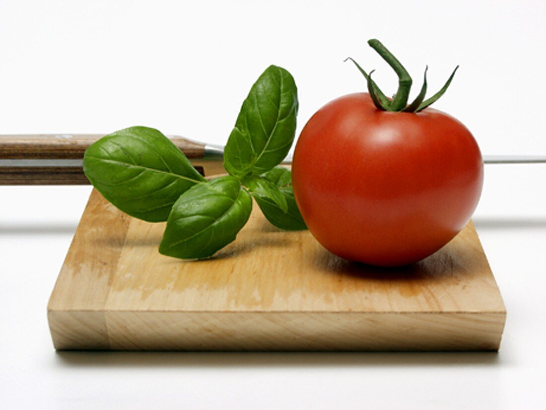Tomato with Basil on Wooden Board with Knife