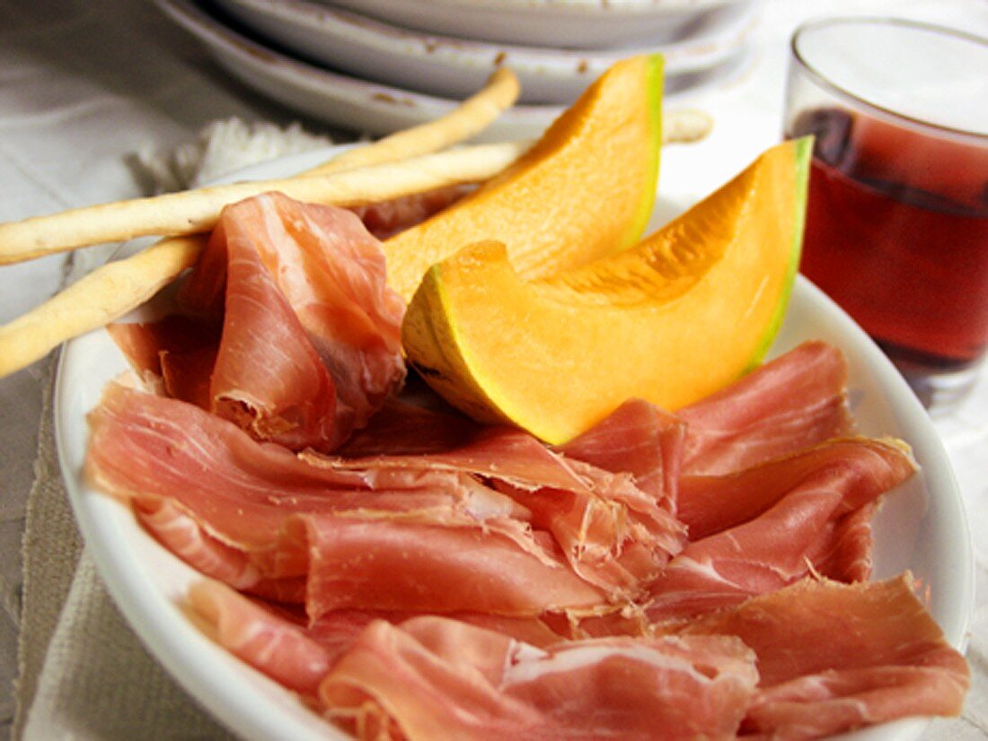 Prosciutto mit Melone und Grissini; Rotwein